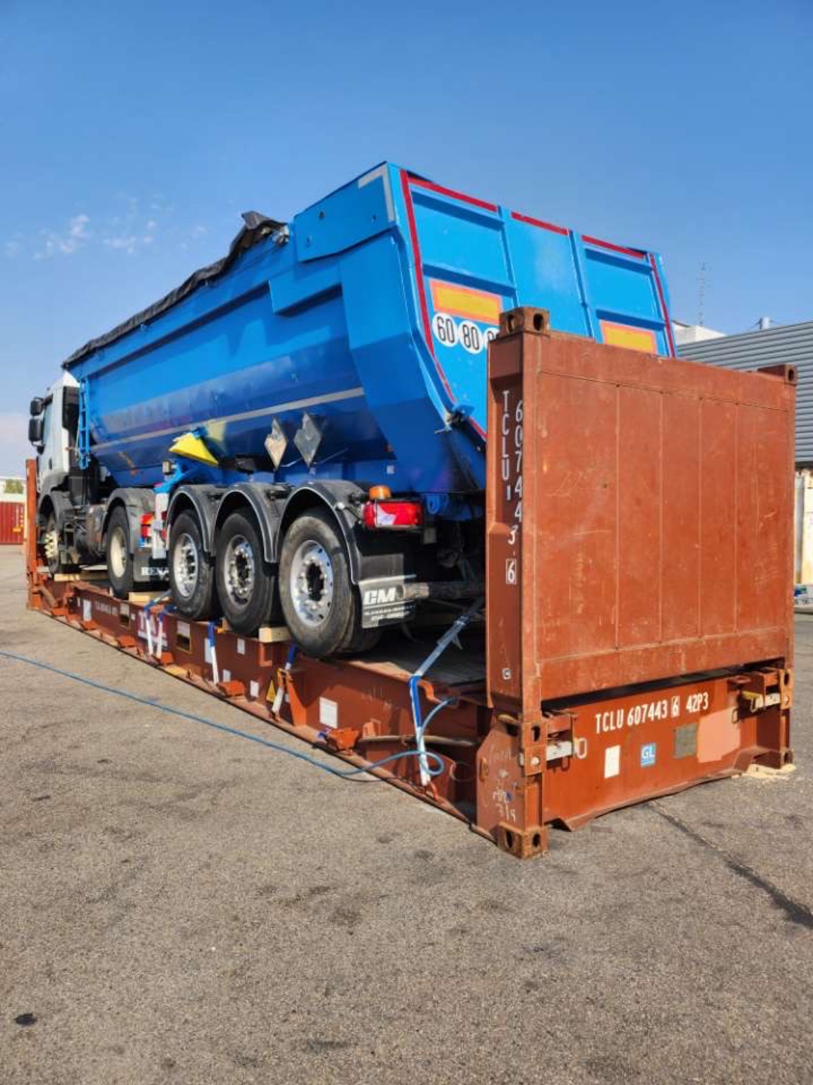 Camion-benne bleu placé sur flat rack